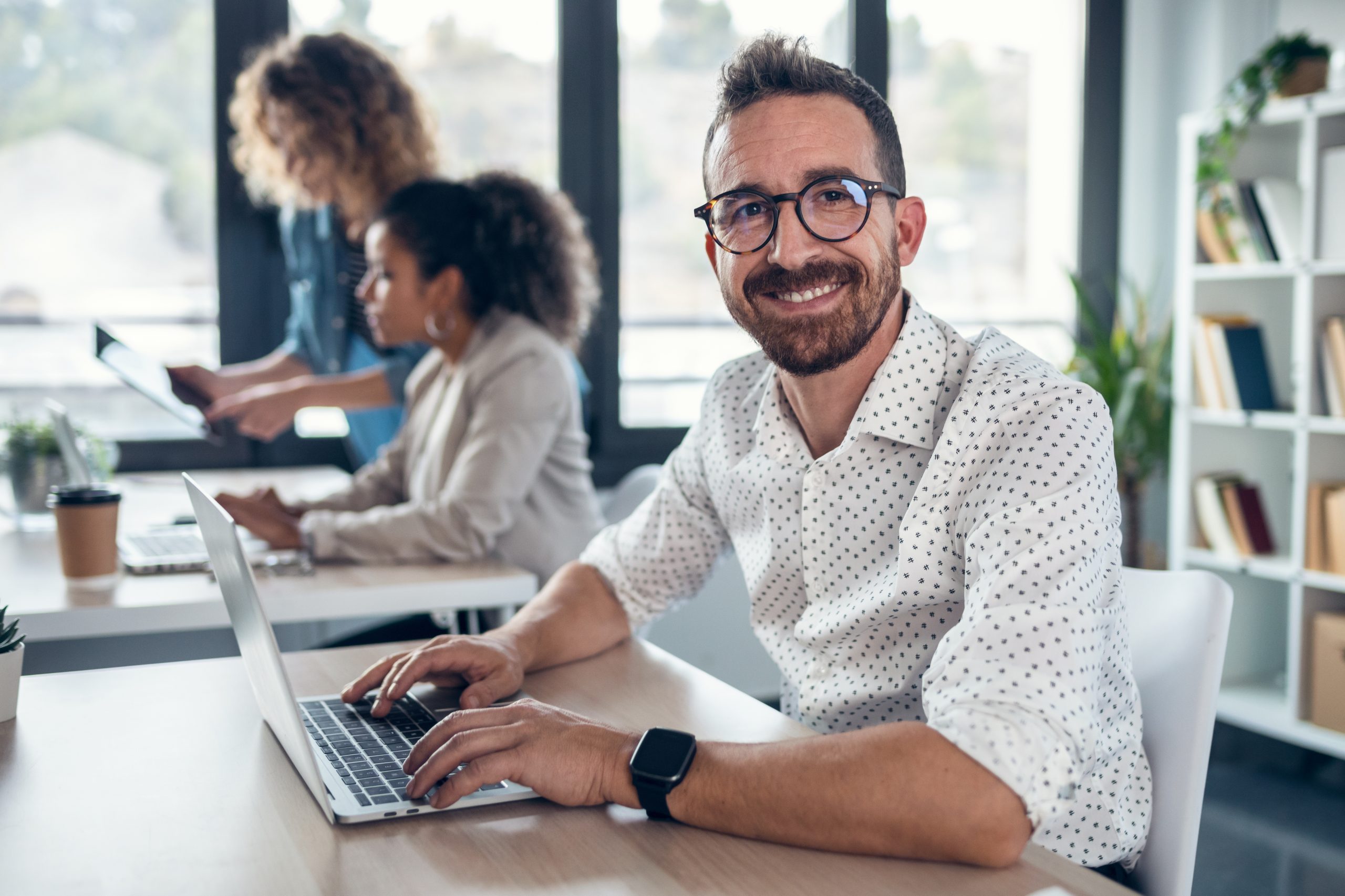 Handsome entrepreneur looking at camera while using the computer